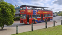 image of red tourist bus with passengers driving down street