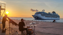image of two musicians on the dock with a cruise ship in background