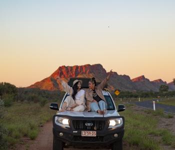 Friends sitting on 4WD bonnet on the side of the road
