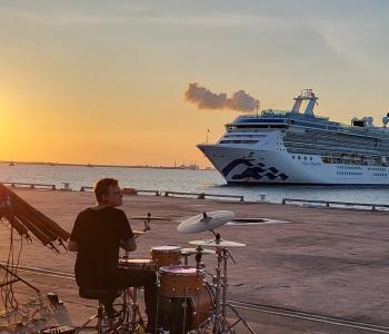 image of two musicians on the dock with a cruise ship in background