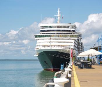 cruise ship docked at wharf with clouds behind