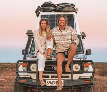 couple sitting on bonnet of 4WD in remote location