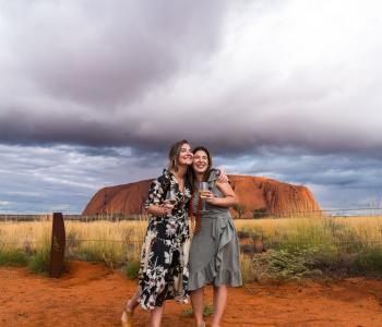 image of women hugging in from of Uluru