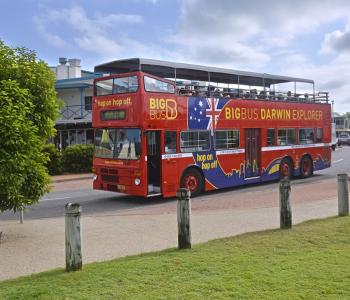 image of red tourist bus with passengers driving down street