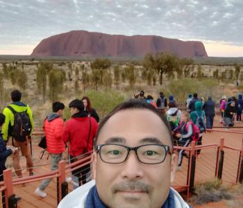 image of Takahiro with people and Uluru in background