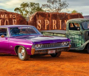 Red CentreNATS cars in front of the Alice Springs sign