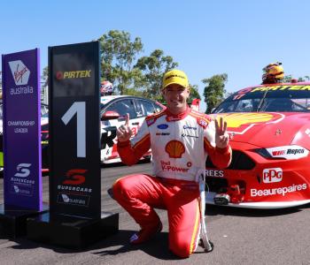 Supercar Driver posing next to signage