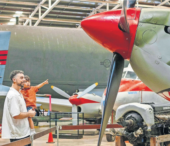 Father Holds his young son as they look up to a World War 2 era fighter jet at the Darwin military museum