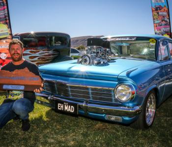 man with trophy infront of car