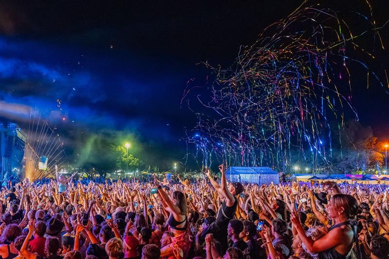 Crowd with arms raised in front of a music stage at night